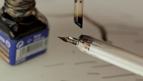 close-up shot of a hand filling a fountain pen with ink from a bottle, focus on pen and ink