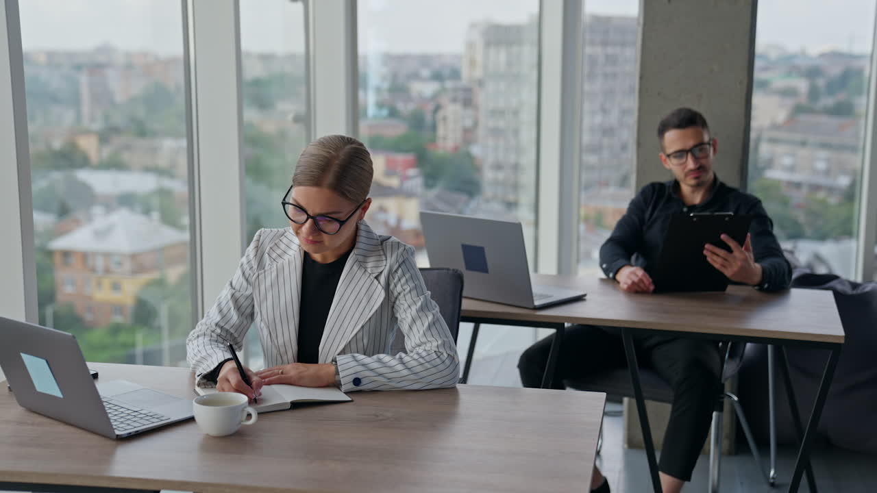Company employees are busy with their routine work in the office. Female is taking notes and man looks at papers bewildered by the results.
