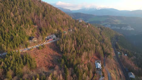 Disparo-Aéreo-De-Un-Dron-Volando-Alto-Sobre-Casas-De-Pueblo-Con-Paisaje-De-Bosque-Montañoso-En-Semmerling,-Austria-Durante-La-Hora-Dorada