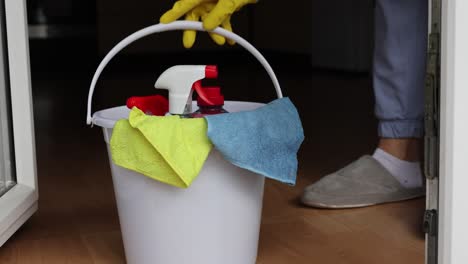 4k video footage detergents in a bucket on the floor and woman cleaning her home in the background