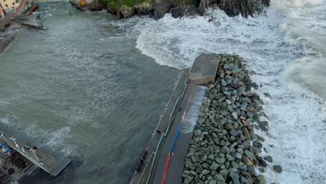 enorme ola de mar espumosa rompiendo en el muelle de piedra antes de fluir hacia el puerto