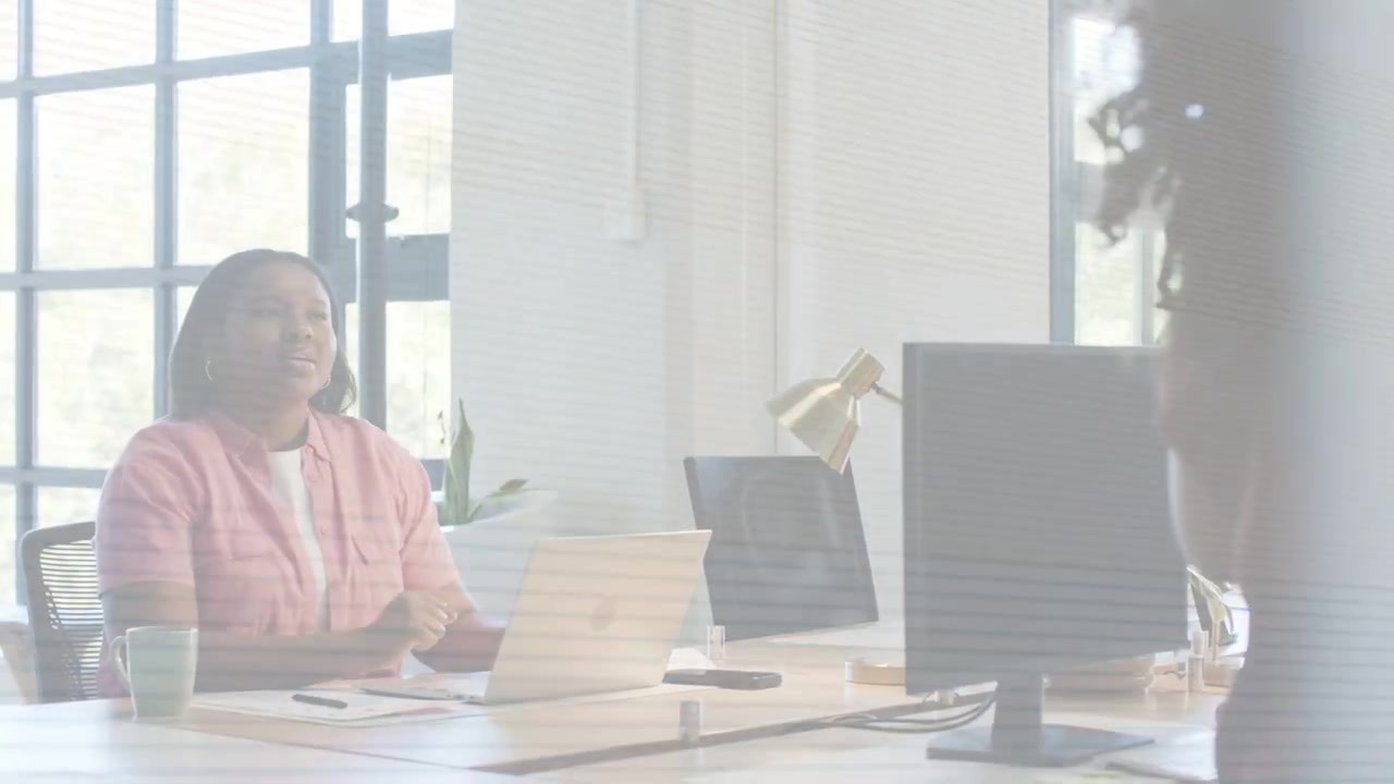 Donna seduta che interrompe la digitazione sul laptop e risponde a un collega in ambito aziendale, con una sovrapposizione a bande che si dissolve.