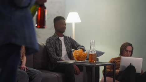 black man puts beer on table watches baseball with friends