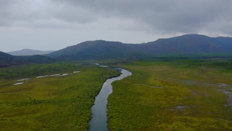 Drone-shot-traveling-forward-above-vast-empty-lands-scattered-with-some-lakes-and-rivers-with-some-mountains