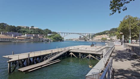 sunny riverfront promenade with a view of arrábida bridge and a helicopter in porto, portugal