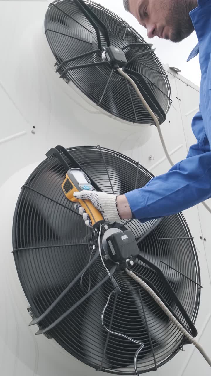HVAC Technician Inspecting Industrial Cooling Fans with Infrared Thermometer