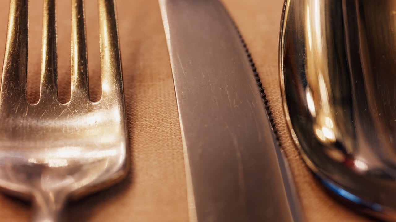 Close up of a fork, knife and a spoon on a napkin on a table at a restaurant