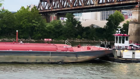 barge ship and tug boat cross under bridge in ohio river, cincinnati, usa