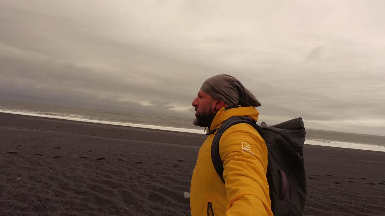 Un uomo che cammina lungo la spiaggia di sabbia nera di Reynisfjara