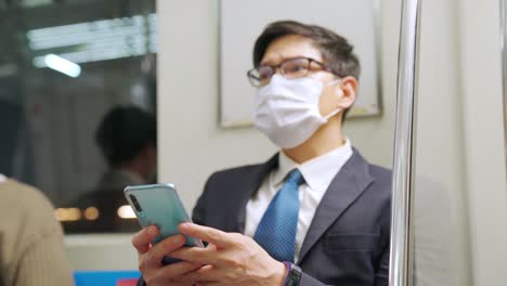 Traveler-wearing-face-mask-while-using-mobile-phone-on-public-train