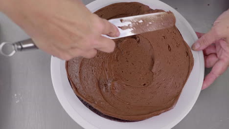 Top-down-shot-of-chocolate-cake-being-topped-with-butter-cream