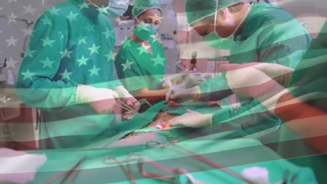 animation of waving american flag against team of diverse surgeons performing surgery at hospital