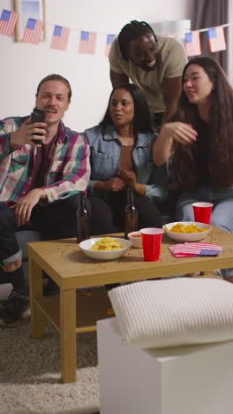 Vertical-Video-Of-Friends-At-Home-Celebrating-With-Party-For-American-Independence-Day-4th-July-Making-Video-Call-On-Mobile-Phone-1