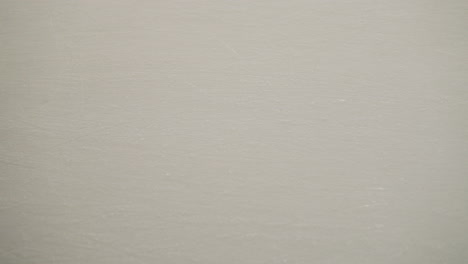 a close-up view of a pristine white skiing ground with a boy in black trousers skiing on the surface. capturing the texture and activity on the skiing ground