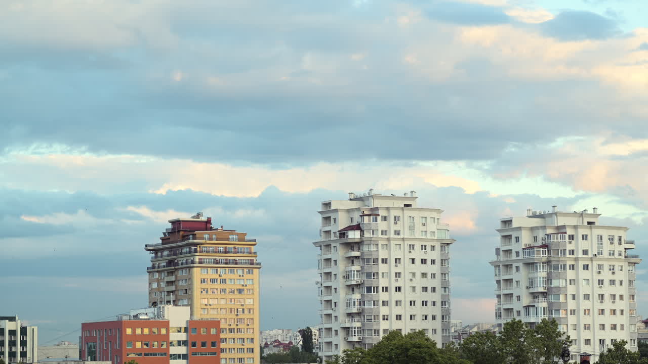 Time lapse of city skyline with tall residential buildings under cloudy sky