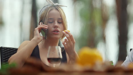 focused girl speaking mobile phone outdoors. woman eating cherry tomato outside