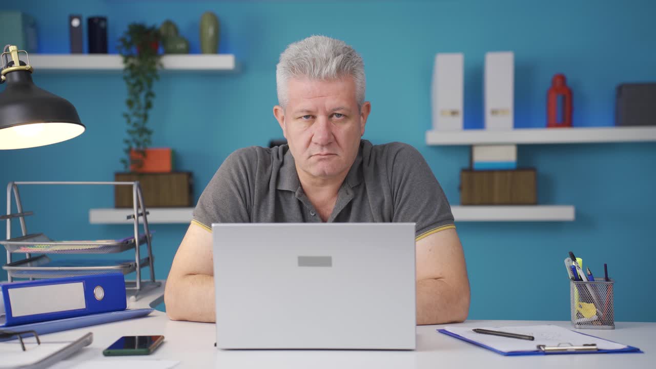 Home office worker man looking dull at camera.