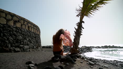 Chica-De-Atrás-En-Una-Playa-Ventosa-Junto-A-La-Palmera