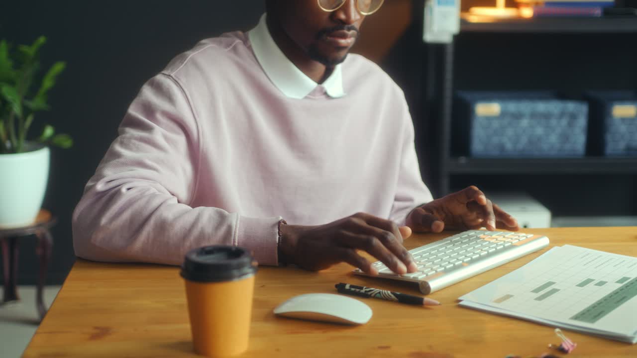 Close-Up of Black Man Typing on Computer Keyboard at Office Desk
