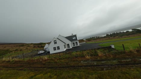 drone volando rápido hacia una casa blanca sobre una colina en irlanda