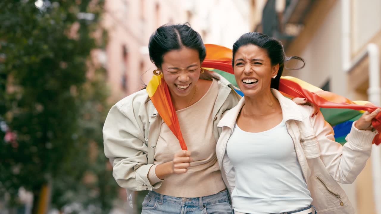 Two women celebrate LGBTQ+ pride and diversity with a rainbow flag in an urban setting