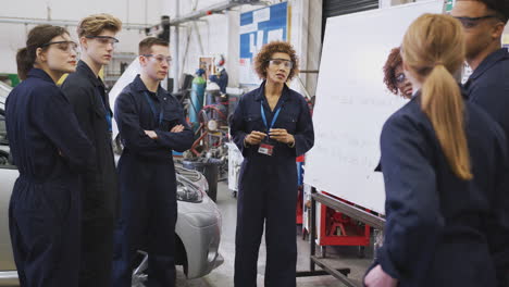 students studying auto mechanic apprenticeship at college asking female tutor questions