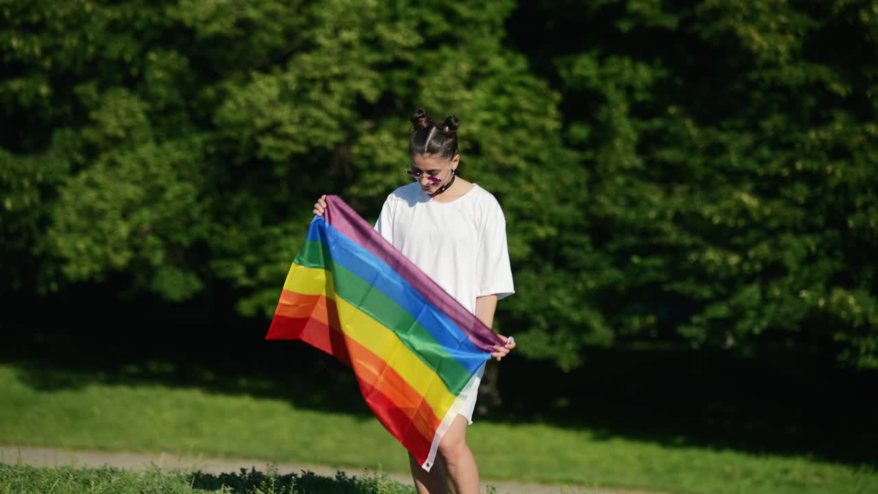 Young woman holding a rainbow flag in a park