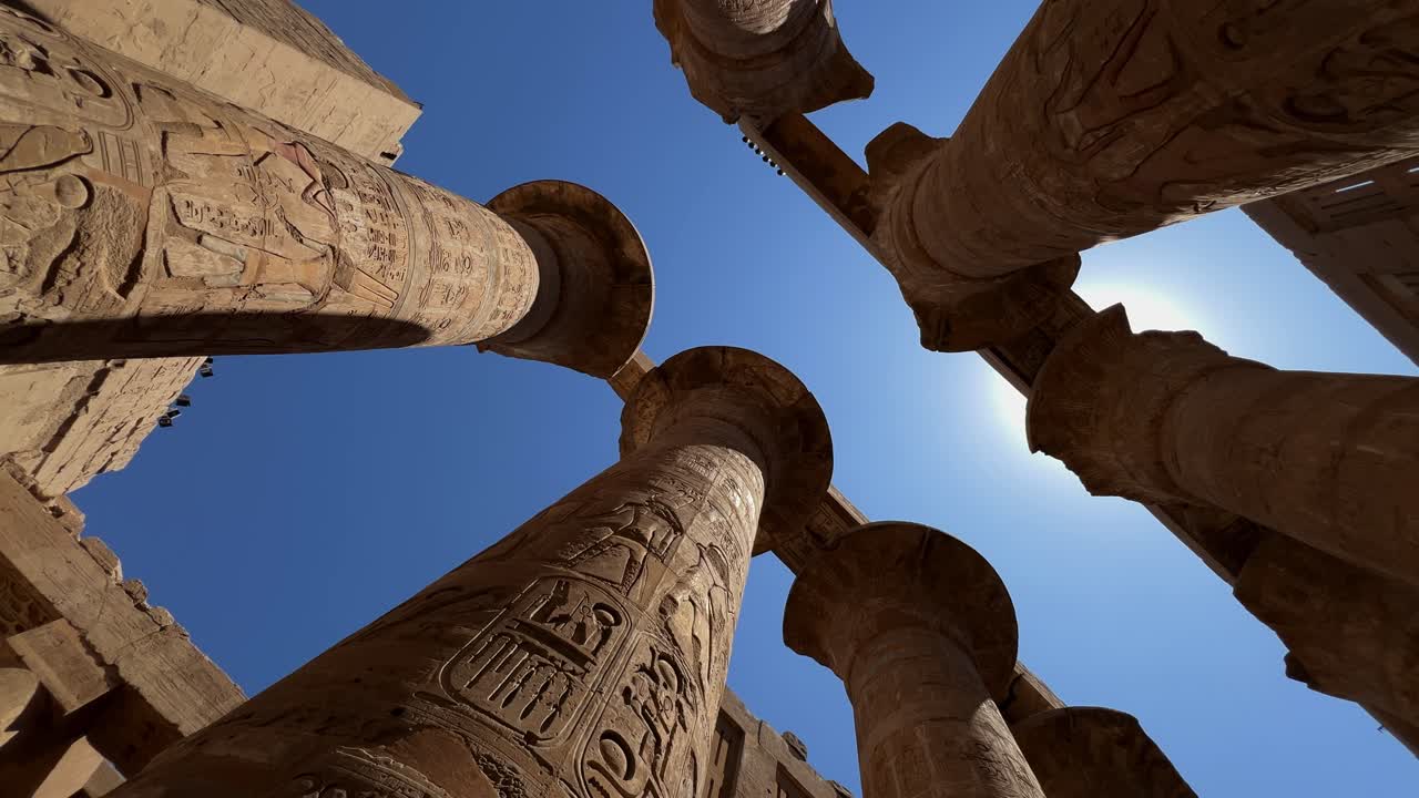 Low-angle panning shot of the massive columns in the Great Hypostyle Hall at Karnak Temple, Luxor, Egypt. For travel, history, or documentary use