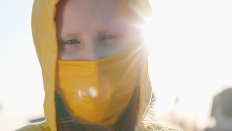 portrait of a girl in a yellow hood and a yellow protective mask