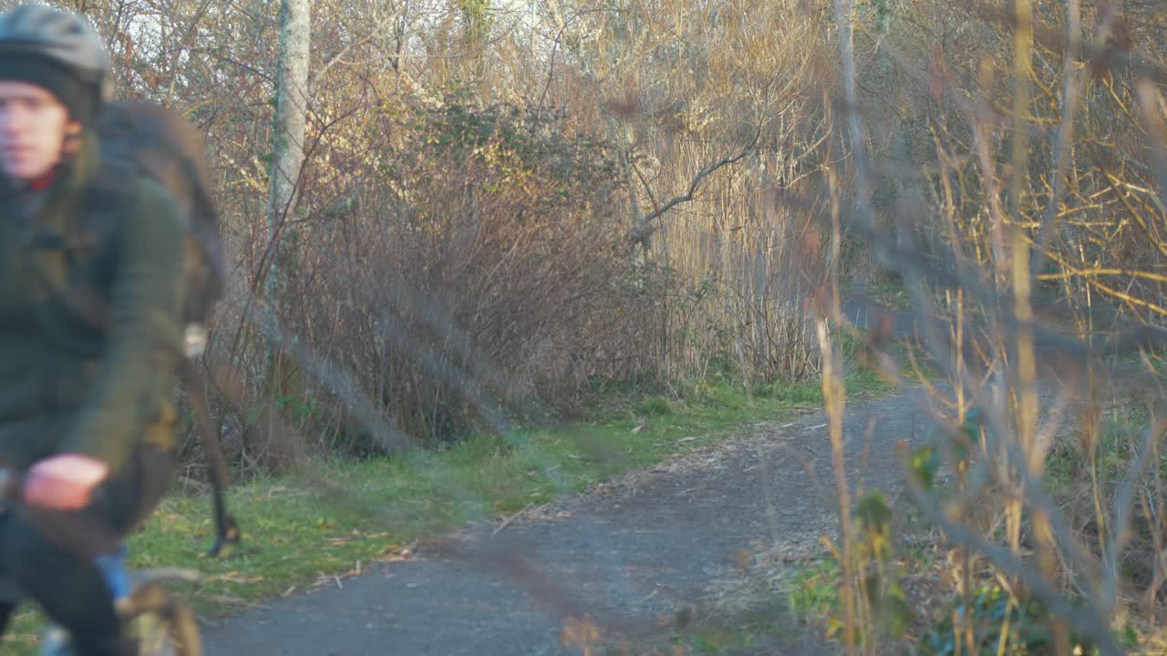 Uomo in bicicletta su un sentiero nel bosco durante l'ora d'oro.