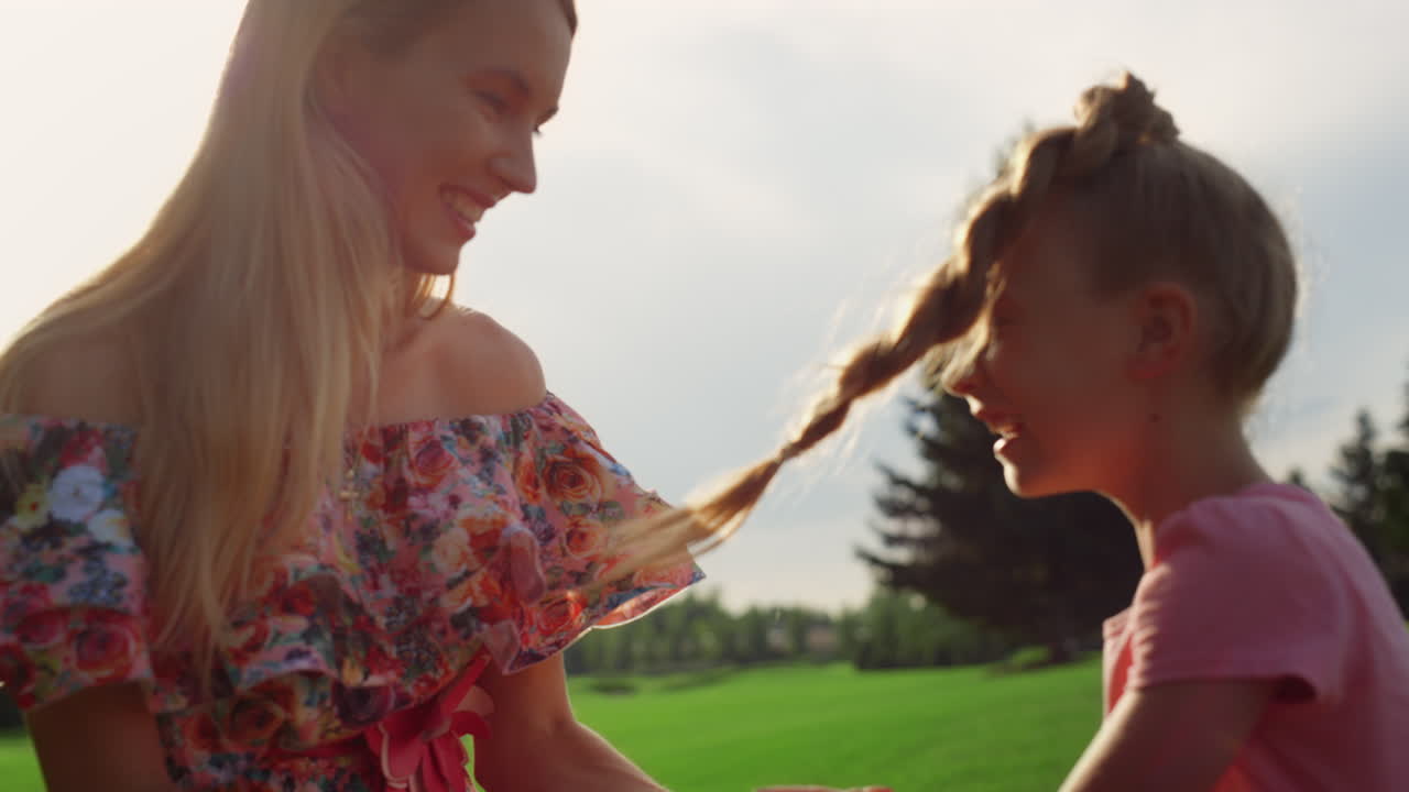 즐거운 가족이 공원에서 장난을 치고 엄마와 딸이 야외에서 즐기고 있습니다.