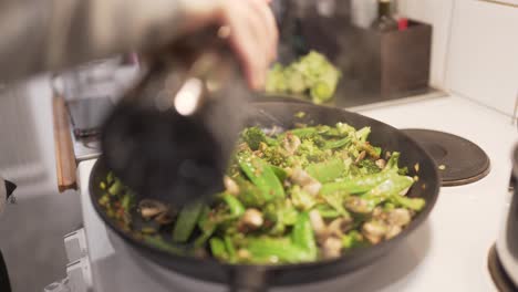 mujer cocinando wok con champiñones, brócoli, chili, fideos, puerro, guisantes y soja-1