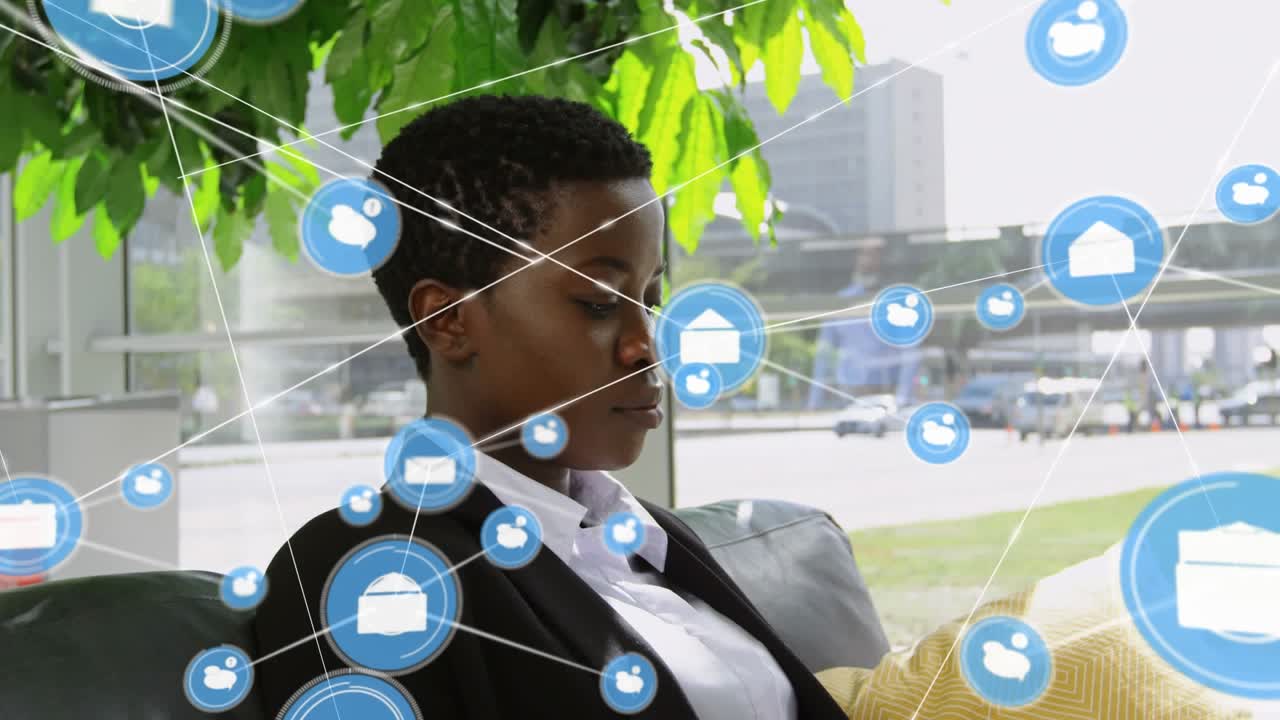 Animation of connected icon over african american businesswoman using laptop while sitting on sofa