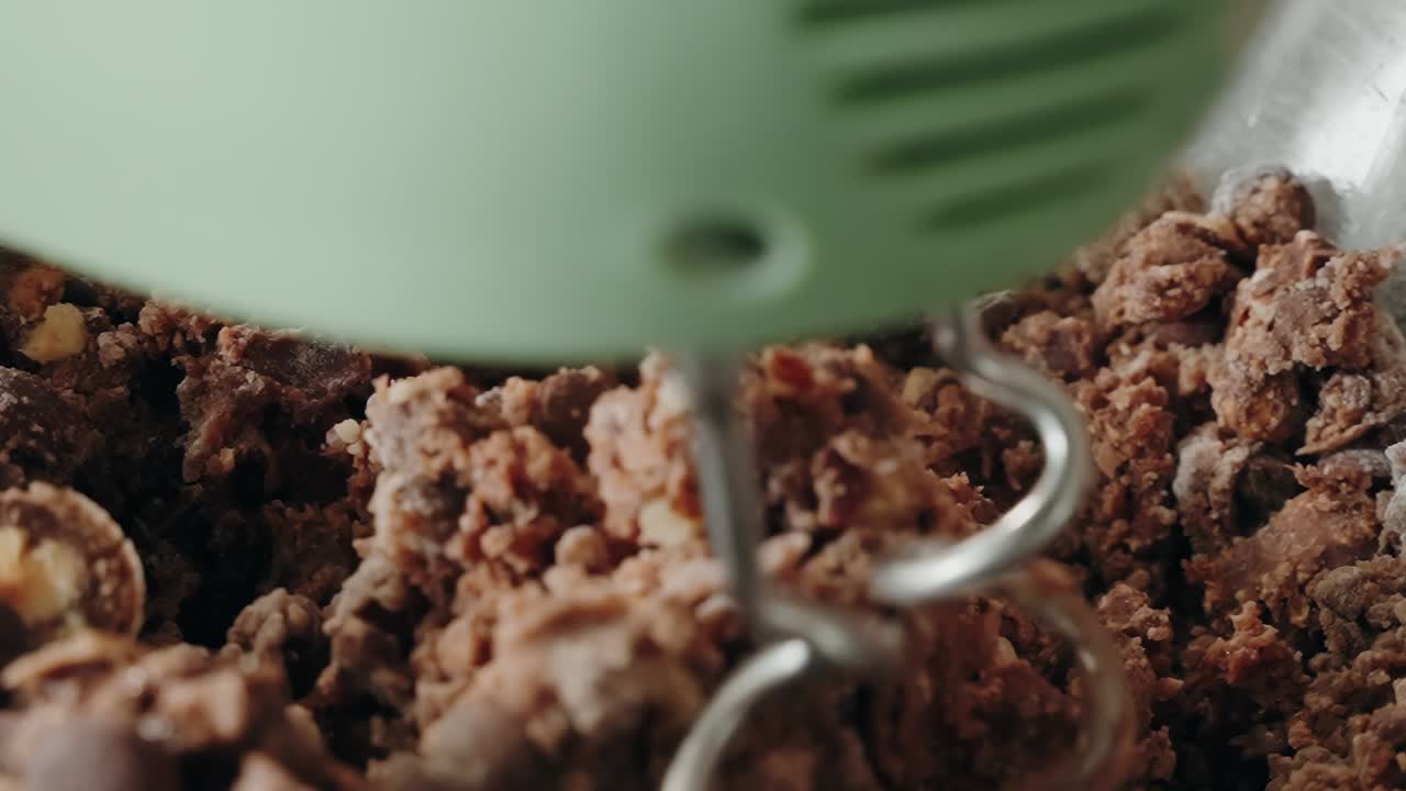 Knethaken mischt Schokoladenkeksteig in einer Schüssel, drinnen bei Tageslicht.