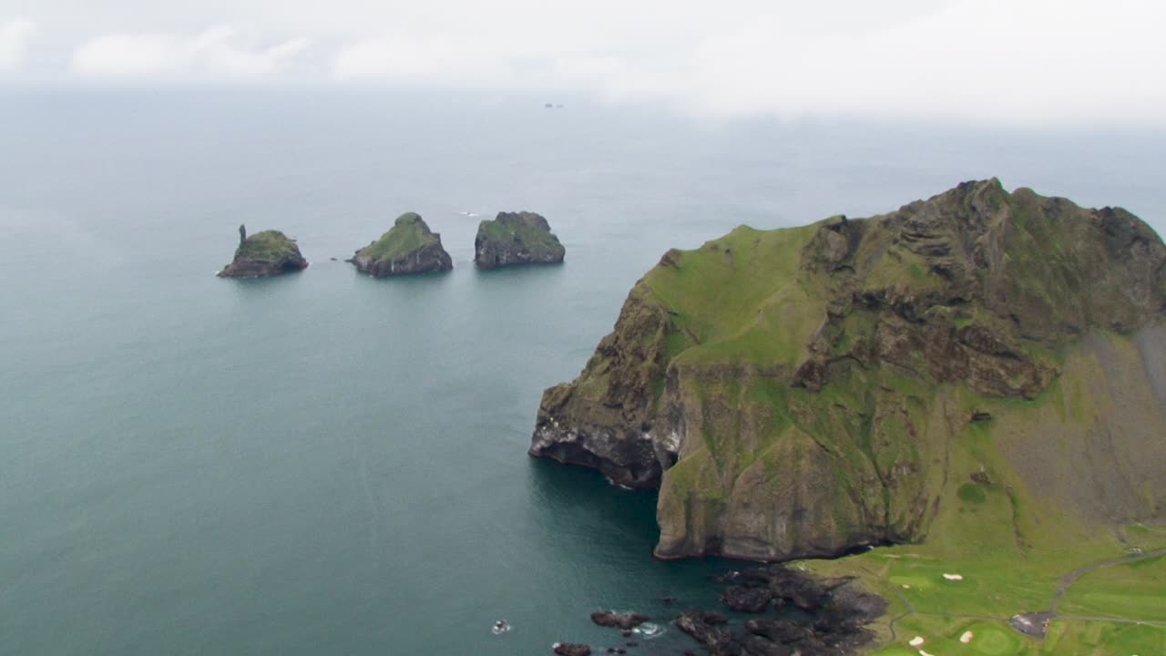 Iceland coastal cliffs with calm sea and distant islands