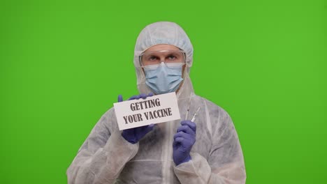 doctor in protective gear holding a sign that reads 'getting your vaccine'