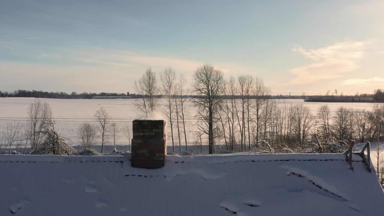 오두막 의 연기 와 눈 인 집 지붕 은 은 겨울 풍경 을 보여 준다