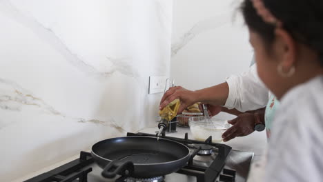 a biracial man pours oil into a frying pan, preparing to cook