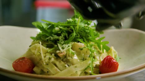 chef wearing black rubber gloves places tomatoes as finishing touch on seafood shrimp pasta