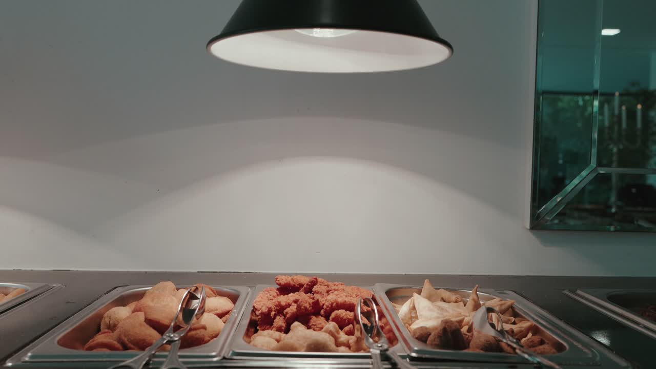 crispy fried snacks on buffet trays under a black overhead lamp