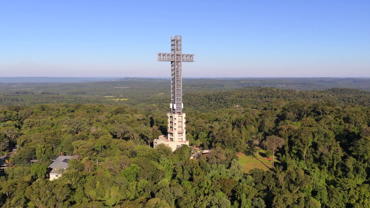 Monumentaler Kreuzturm dominiert die Landschaft des Atlantischen Regenwaldes im Parque Temático de la Cruz, Santa Ana, Provinz Misiones, Nordostargentinien, Drohnen-Vorwärtsflug-Luftaufnahme an einem sonnigen Tag