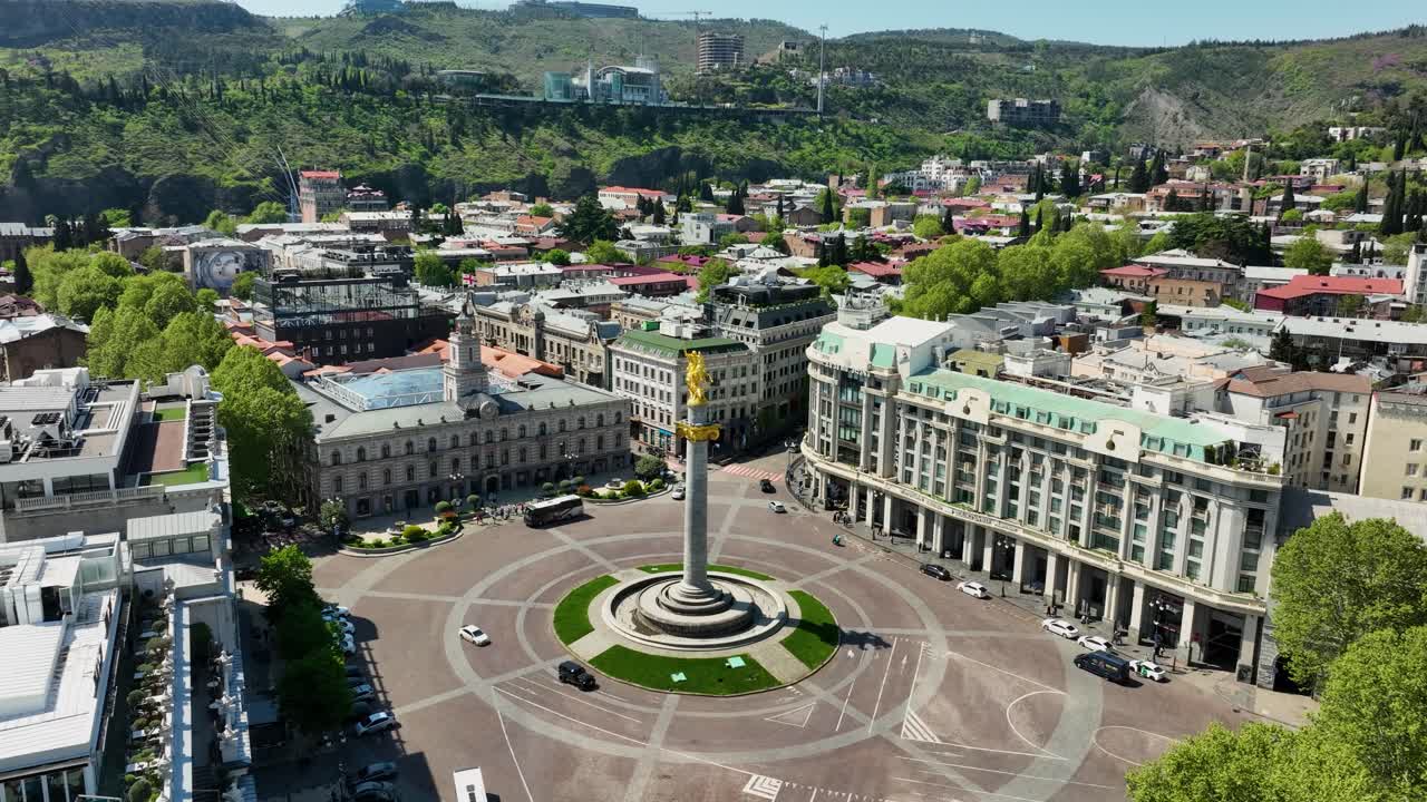 Aerial view of the iconic Liberty Square in Tbilisi surrounded by historic buildings, modern architecture, and green hills in the background