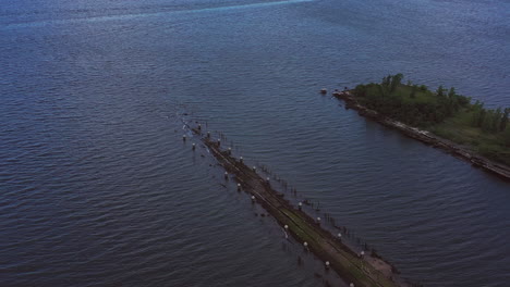 Luftaufnahme-Einer-Drohnenkamera,-Die-über-Einem-Alten-Pier-Im-Wasser-Herabsteigt,-Am-Abend,-Wenn-Die-Wellen-Gegen-Den-Pier-Brechen