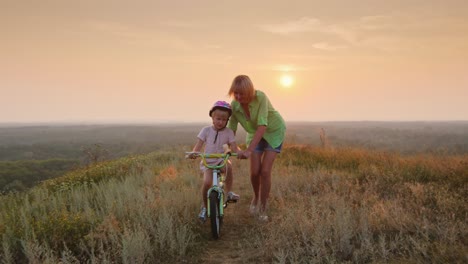 una mujer le enseña a su hija a andar en bicicleta