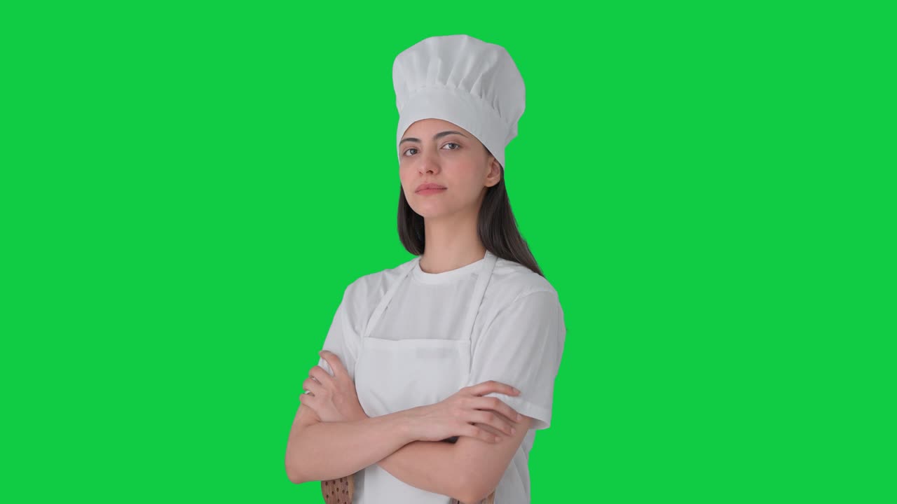 Ritratto di chef professionista indiana in piedi con le braccia incrociate. Green screen