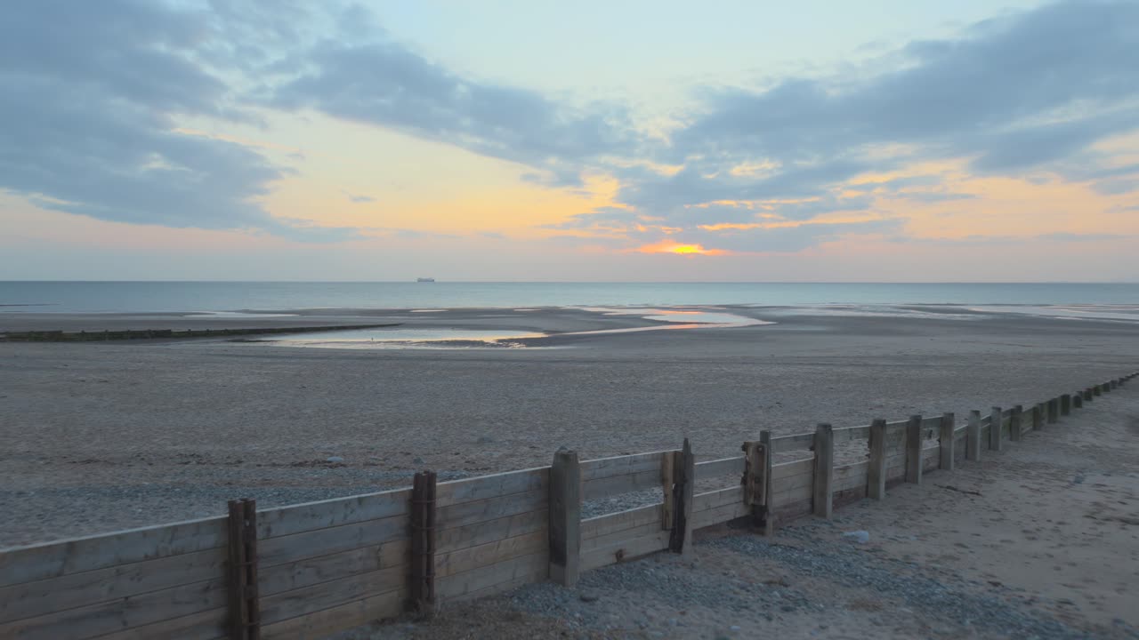 rompeolas de madera con un barco en el horizonte se eleva lentamente durante la puesta de sol en cámara lenta en fleetwood, lancashire, reino unido