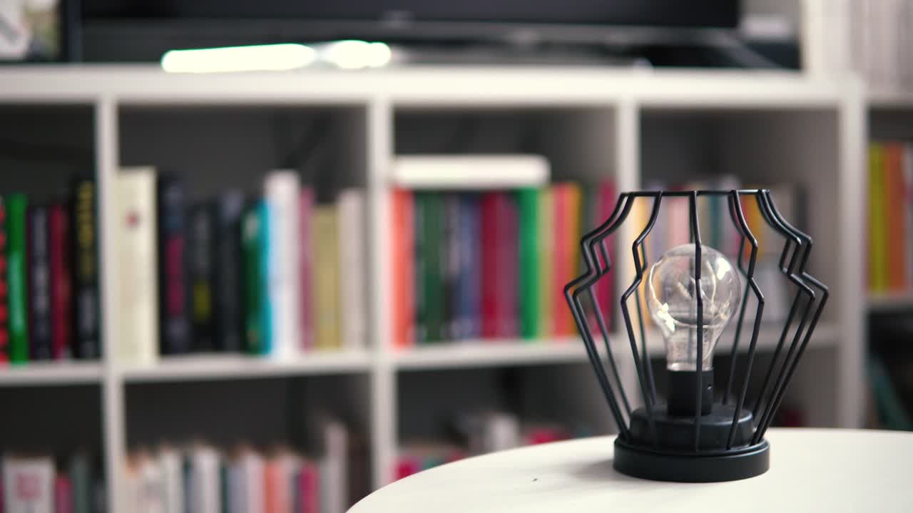 una elegante lámpara sobre una mesa blanca en el fondo hay libros como fondo borroso