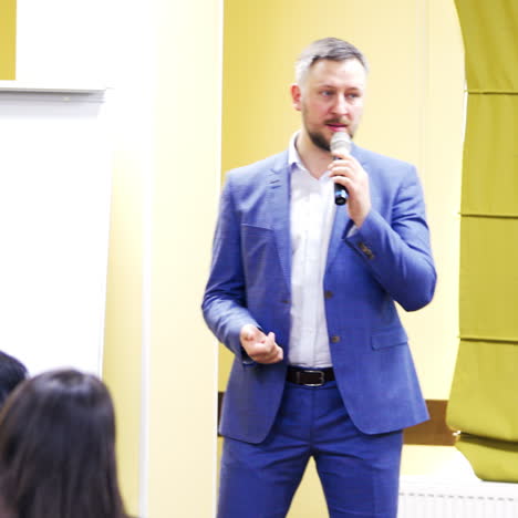 Executive leader speaking with the microphone and gesticulating at public seminar. Professional speaker teaching during the conference.