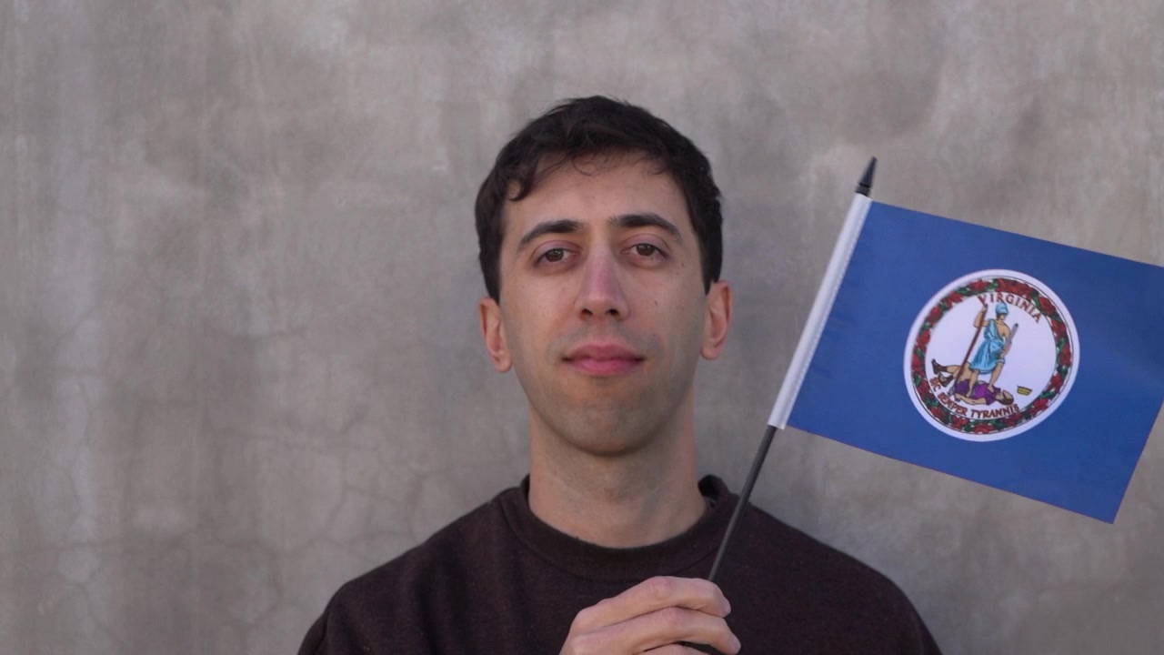 Hombre ondeando la bandera del estado de Virginia. Concepto de territorios de EE. UU. Cámara lenta.