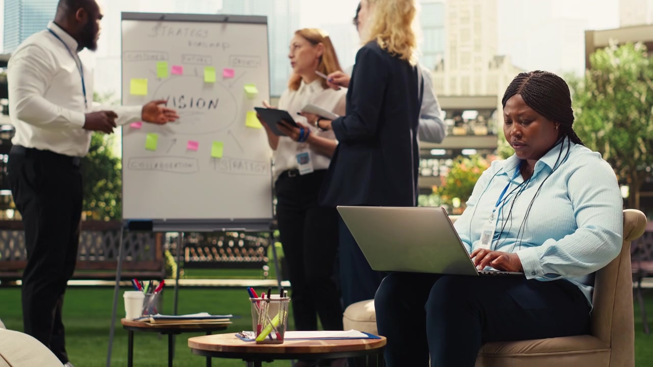 Businesswoman Working on Laptop During Team Meeting in Outdoor Office